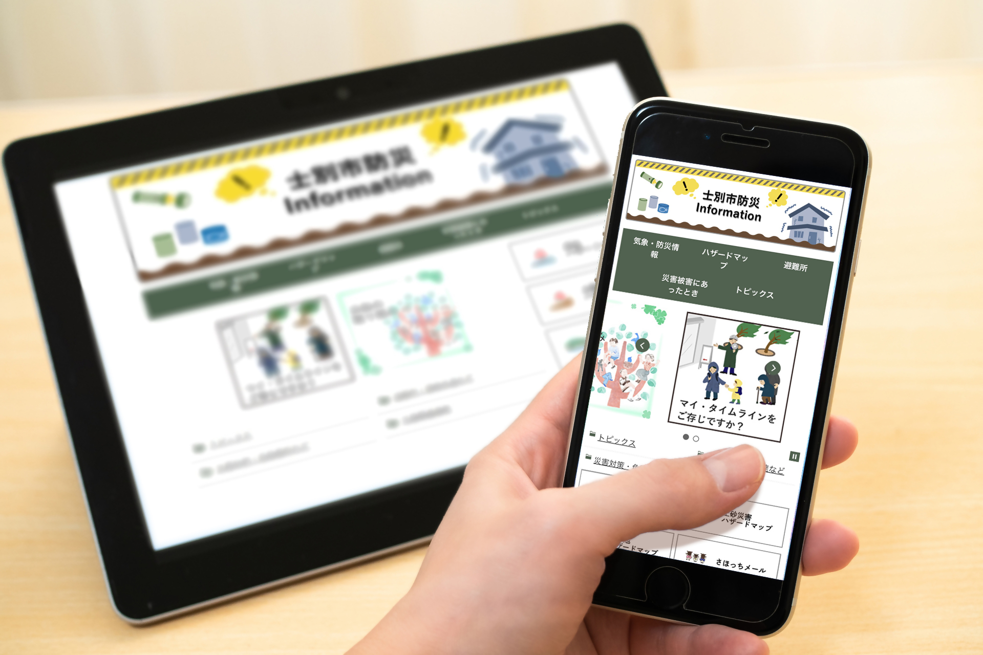 手に持ったスマートフォンと机の上に置かれたタブレットの画面に、士別市ホームページの防災ページが映っている様子