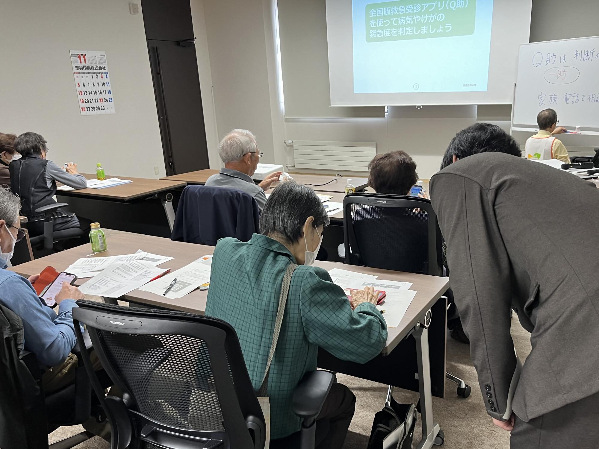 令和5年11月1日に行われた第2回スマホ教室の様子。受講者の方がアシスタントの方に教えてもらいながらスマホの操作を実践している。