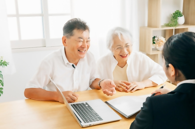 高齢者の夫婦がセールスの人から説明を聞いている様子