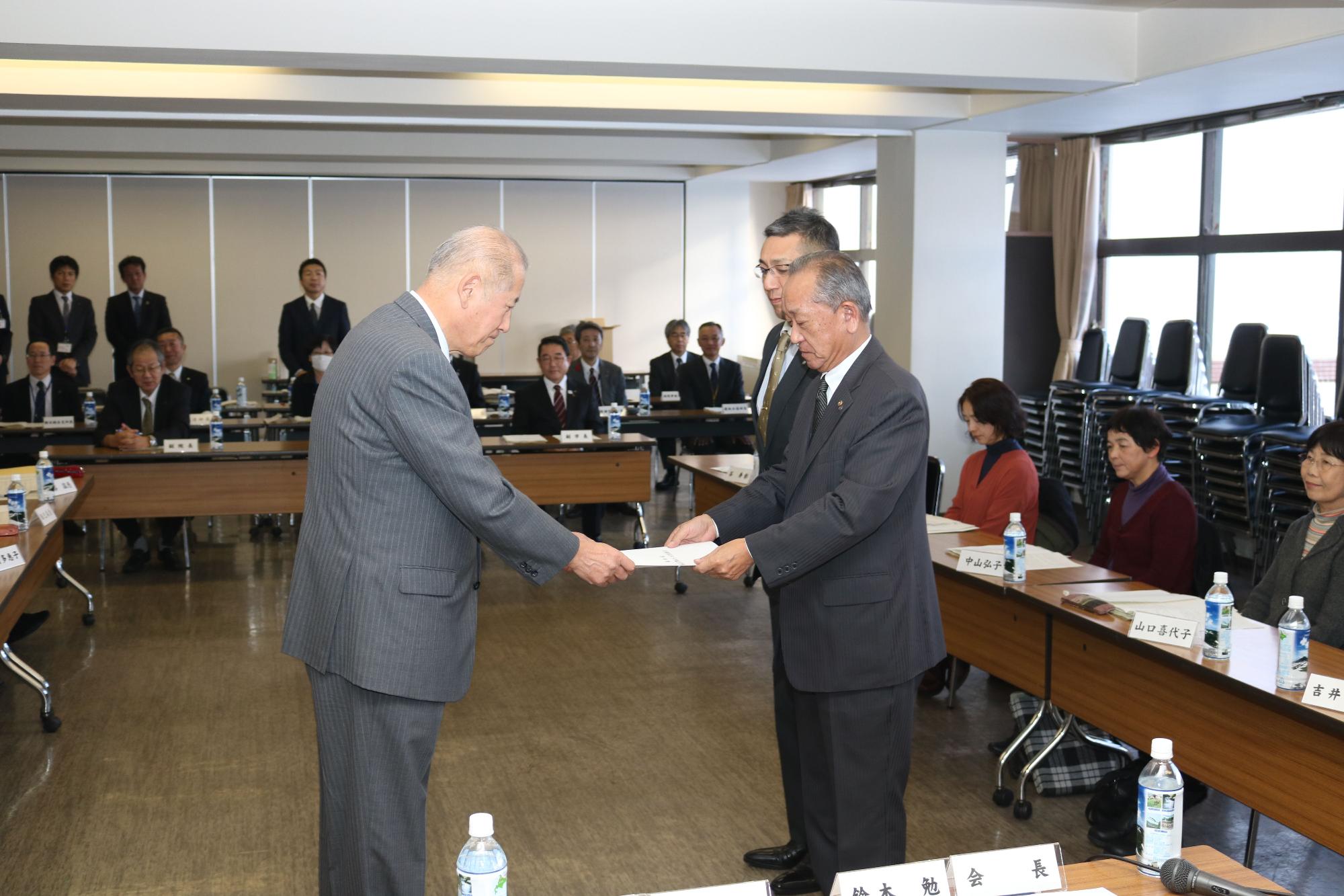 鈴木会長、山田副会長から牧野市長に答申書を手渡ししている振興審議会での写真