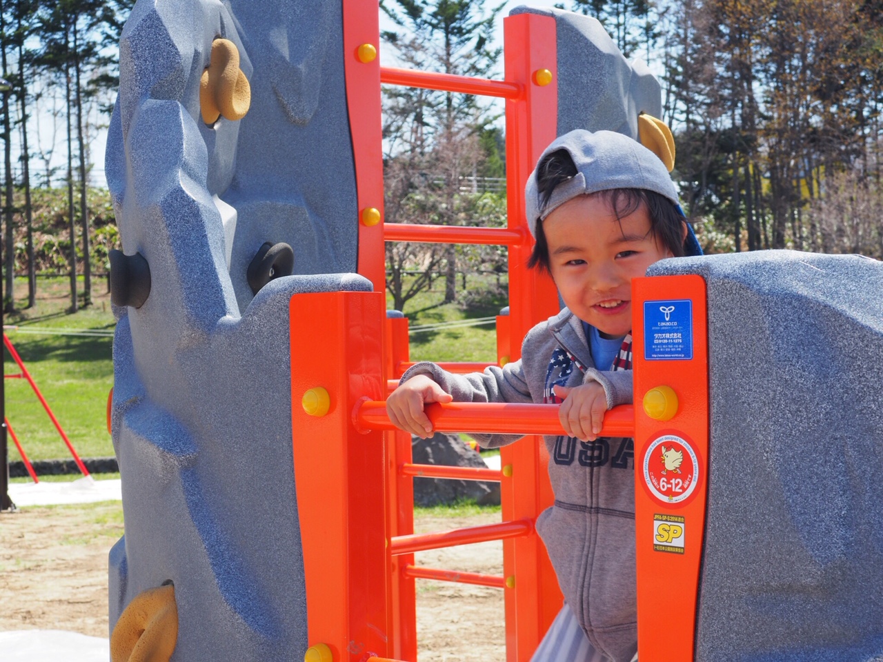 遊具で遊ぶ笑顔の男の子を写した写真