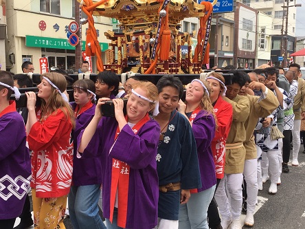 留学生の人達が法被を着てお神輿を担いでいる写真