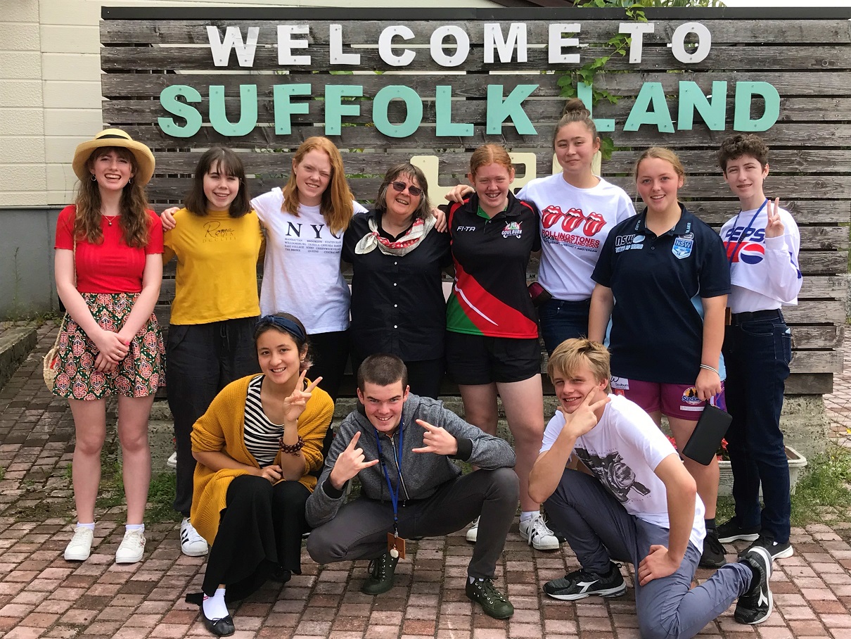 WELCOME TO SUFFOLK LANDと書かれた前にゴールバーンマルワリーの留学生がいろいろなポーズを取りながら記念撮影をしている写真