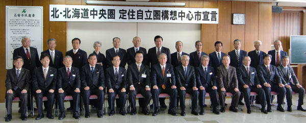 北・北海道中央圏定住自立圏構想中心市宣言と書かれた横断幕と関係者の方々が並んだ記念写真
