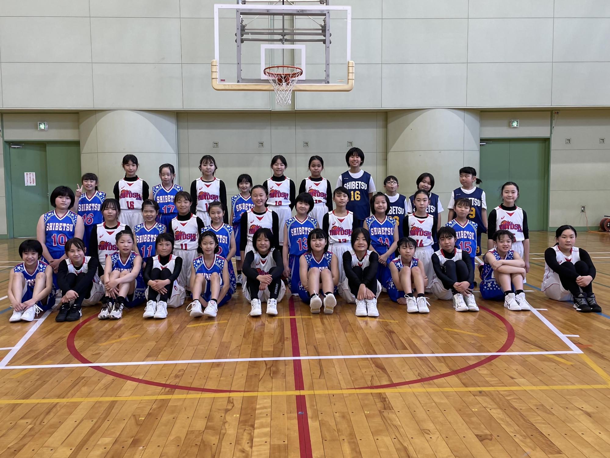 体育館でユニフォーム姿の女の子達が記念撮影をしている写真