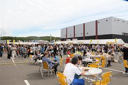 丸テーブルが設置された会場で食事を楽しんでいる人達の写真