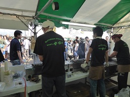 販売ブースでラム串を焼いているスタッフの後ろ姿の写真