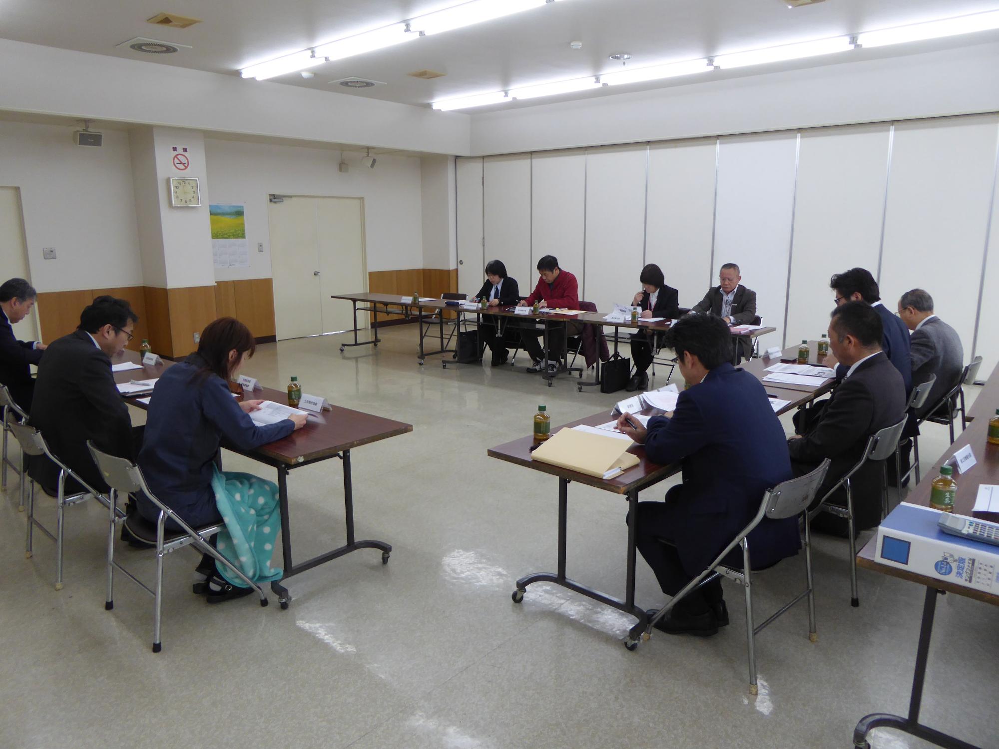 コの字型に設置されたテーブルに置かれた資料を見ながら話し合いをしている参加者の写真