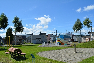 虹の絵が描かれた船の形をした遊具がある公園の写真