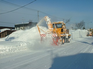 道路を除雪作業をするホイールローダーの後ろにもう1台ホイールローダーが追い掛けて作業をしている写真