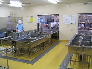 向かい合わせて設置されているシンクに立って作業をしている調理員の写真