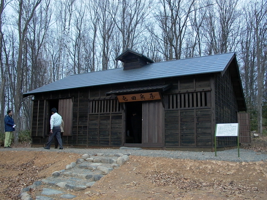 屋根が葺き替えられ、壁板は新しいものに貼り替えられた建物の入り口に「屯田兵屋」と書かれた看板が掲げられている写真