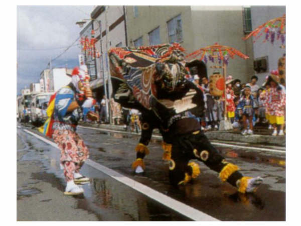 舞を披露している瑞穂獅子舞と沿道で見ている祭りの観客の写真