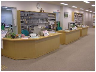 木製の3台の机の上にパソコンやチラシなどが置かれ、壁側の棚に各証明書カードなどが収納された1階カウンターの写真