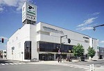 建物前に信号機付きの横断歩道がある、白色の3階建て士別市生涯学習情報センターいぶきの外観写真