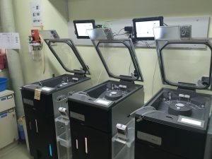 全体が黒く、上部の蓋が開いている3台の内視鏡洗浄機の写真