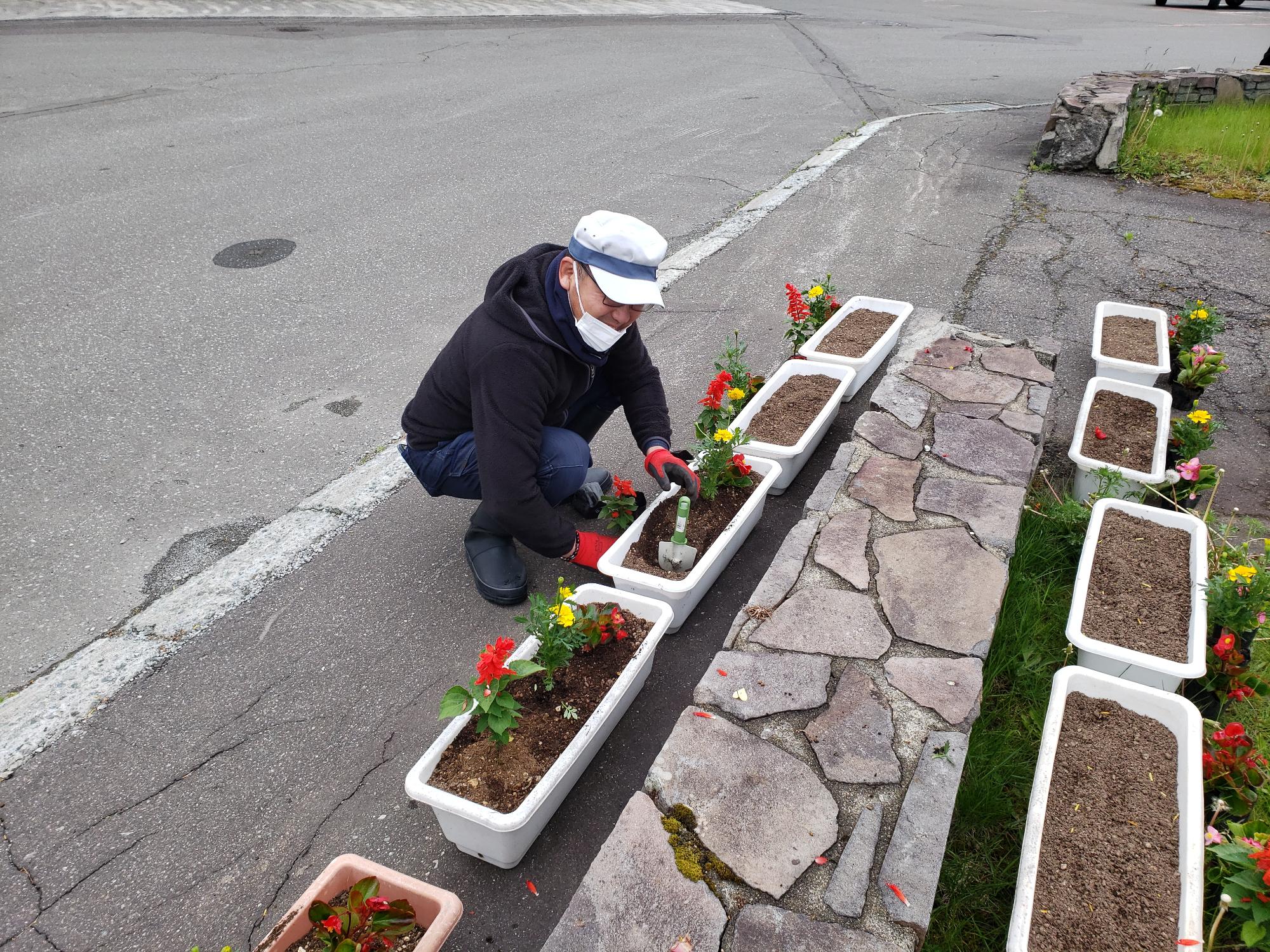 病院応援隊の方が、プランターに花を植えている写真。