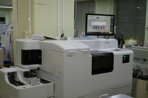 ディスプレイの下に横幅が2メートルくらいある角が丸く施された生化学・免疫検査の機器の写真