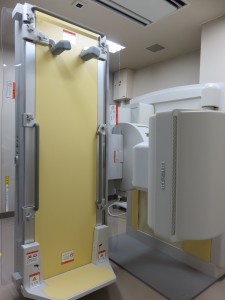 左側に地面に垂直に立てた薄黄色の透視撮影台、右側にX線管装置が設置されたX線TV装置の機器の写真