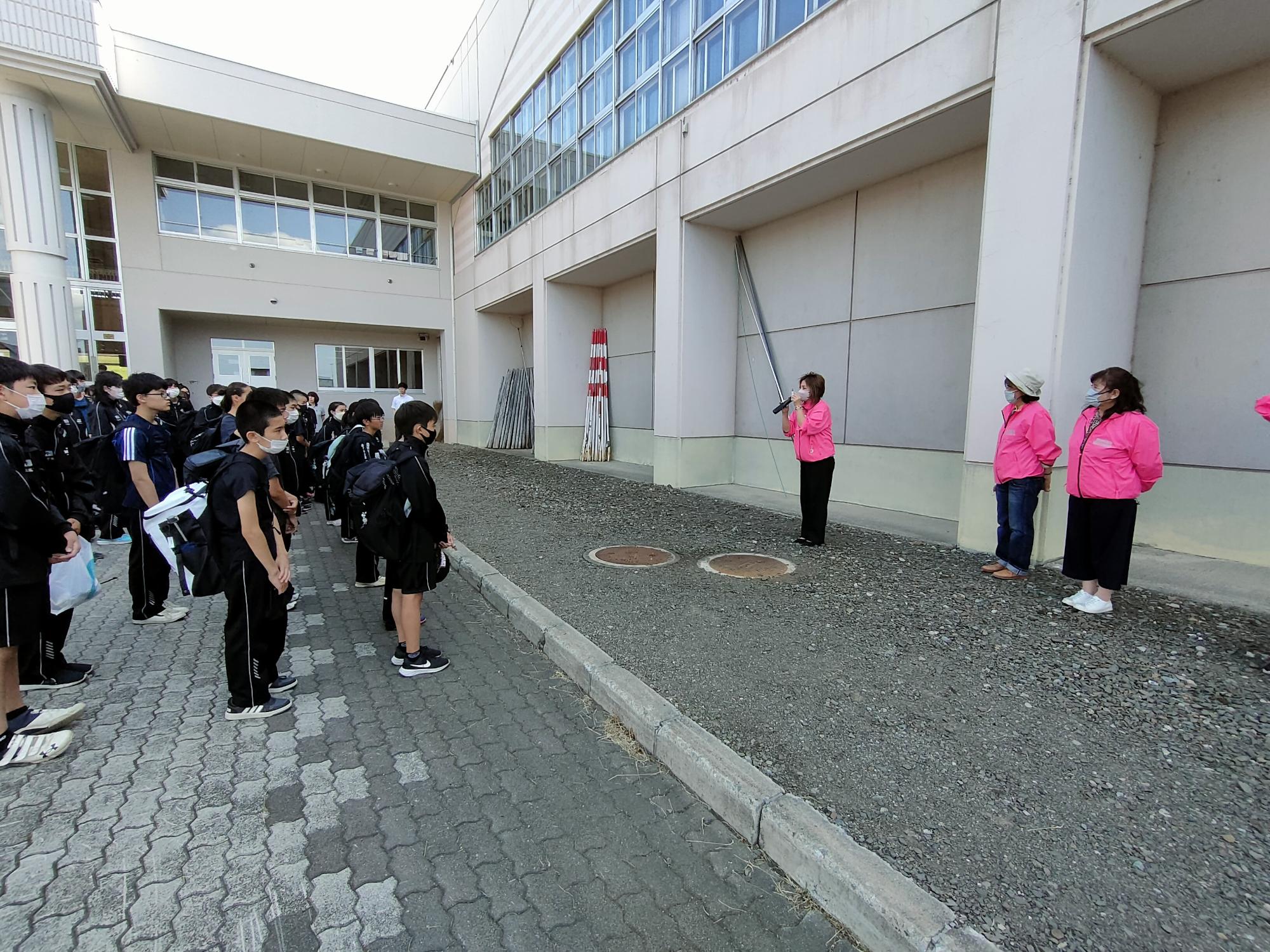 交通安全母の会の役員が、中学1年生に夜光反射材の説明をしている写真