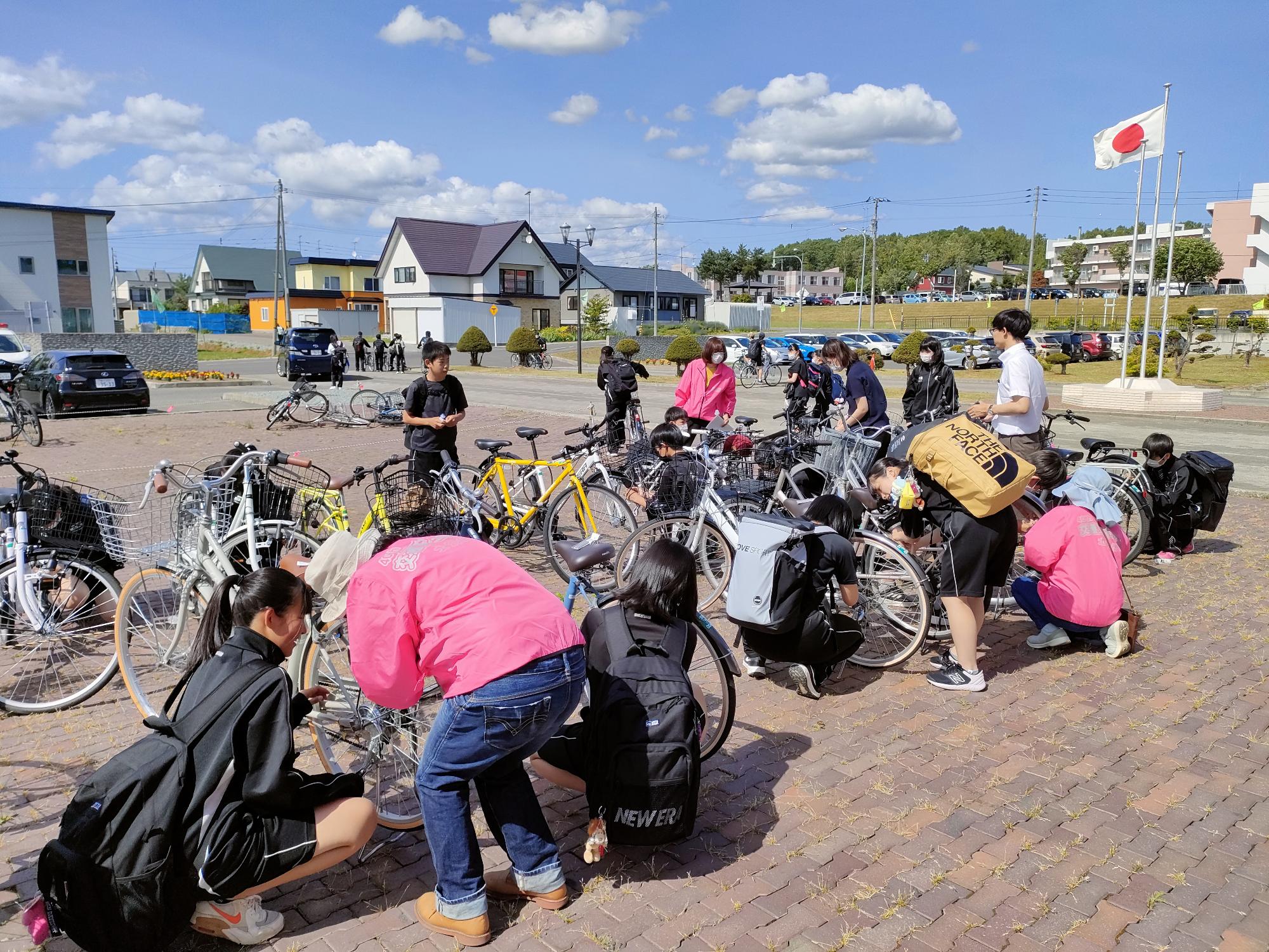中学1年生が交通安全母の会会員と一緒に自転車に夜光反射材を取り付けている写真
