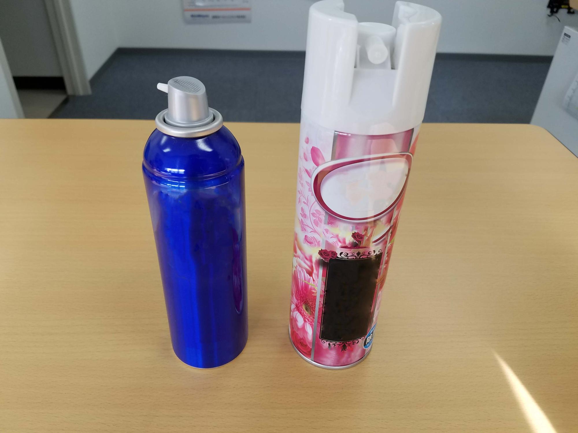 机の上に青色のボトルの育毛剤と消臭スプレー缶が並んでいる写真