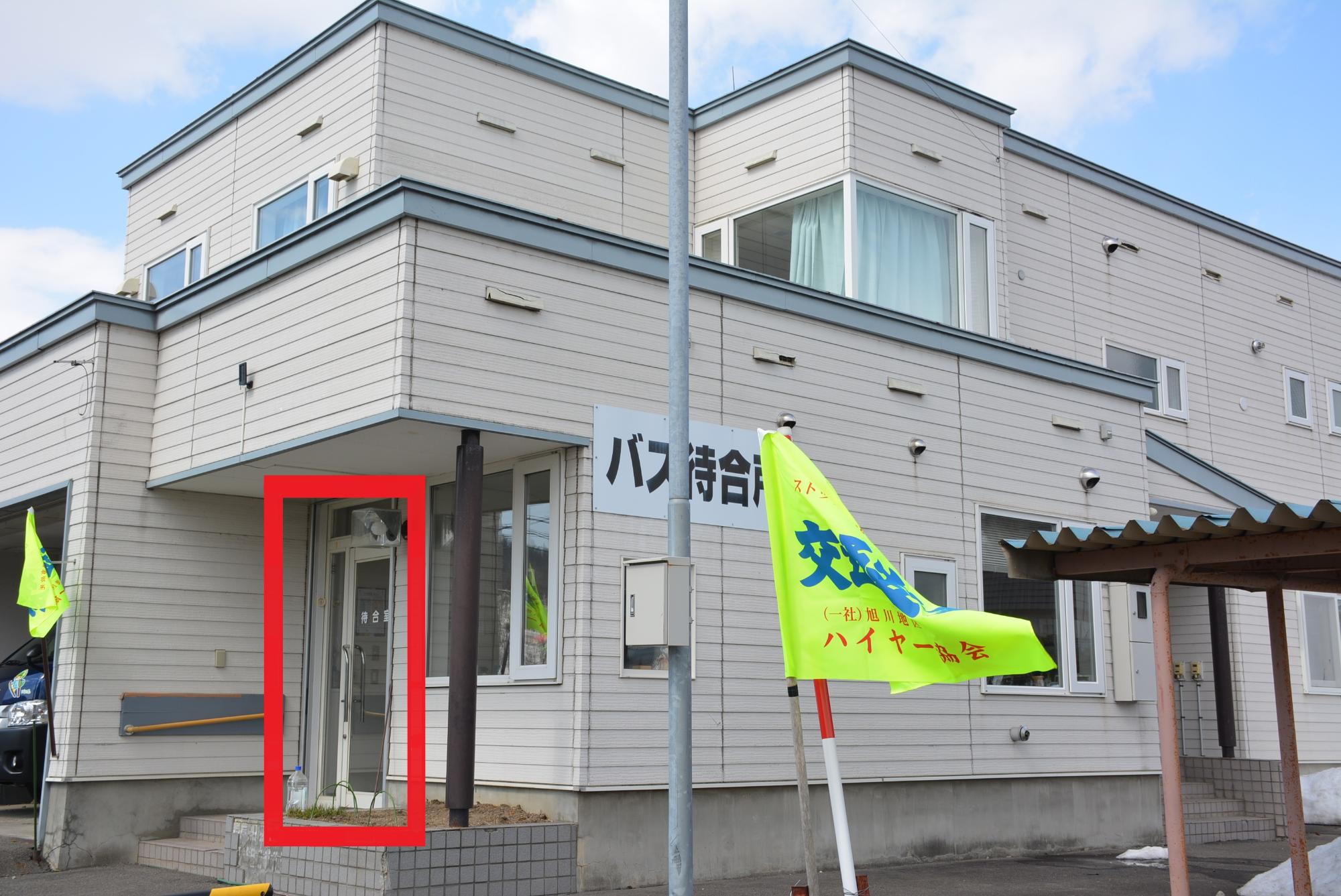 待合室と書かれたドアを赤い枠で囲ってある建物を斜めから撮影した写真