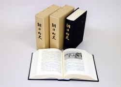 3冊立てて並べられ、1冊開いて置かれている朝日町史の写真