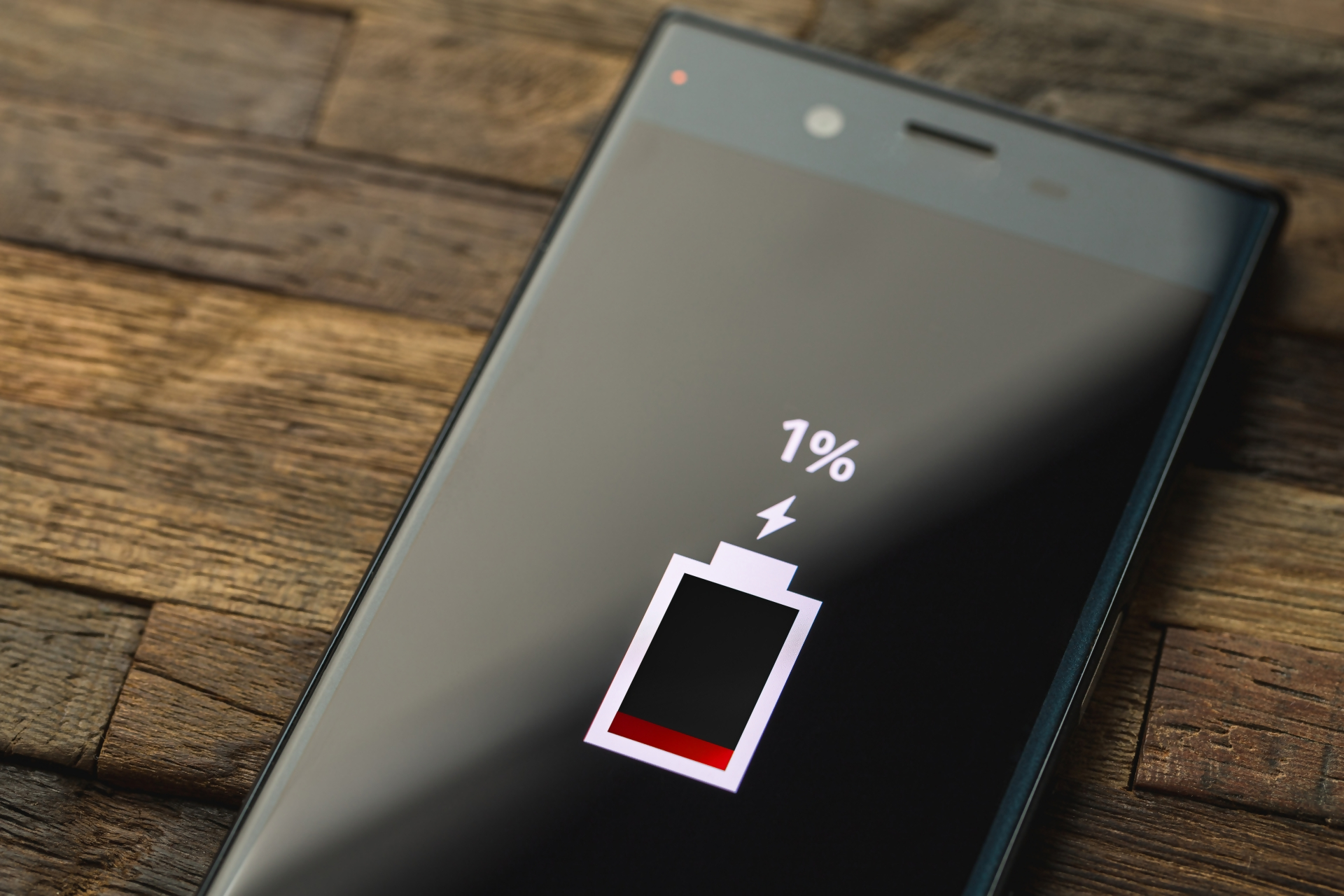 黒色のスマートフォンに充電が残り1パーセントと表示されている画像