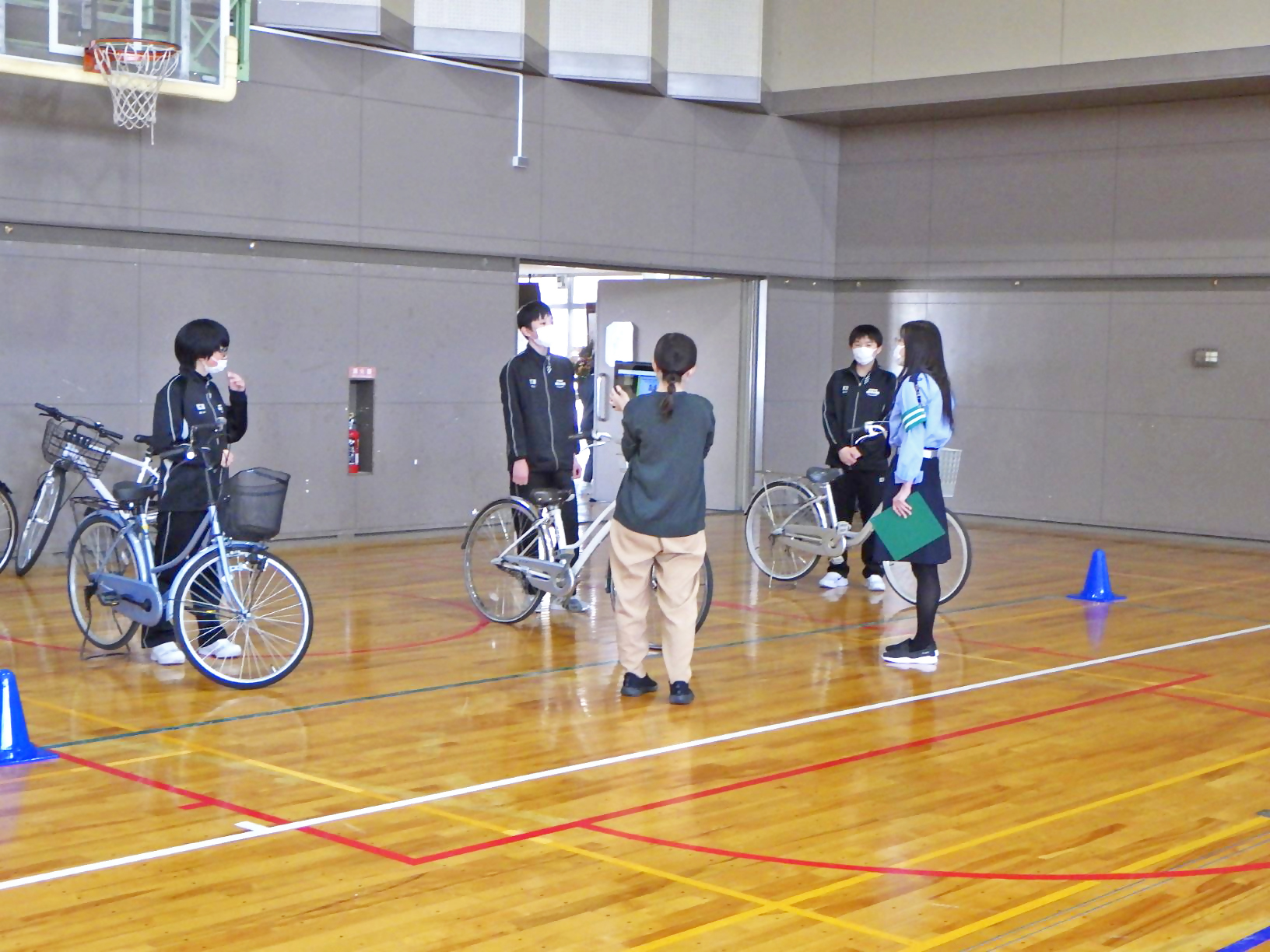 中学校で、安全な自転車の乗り方について指導する「まもってあげ隊」隊員の写真。
