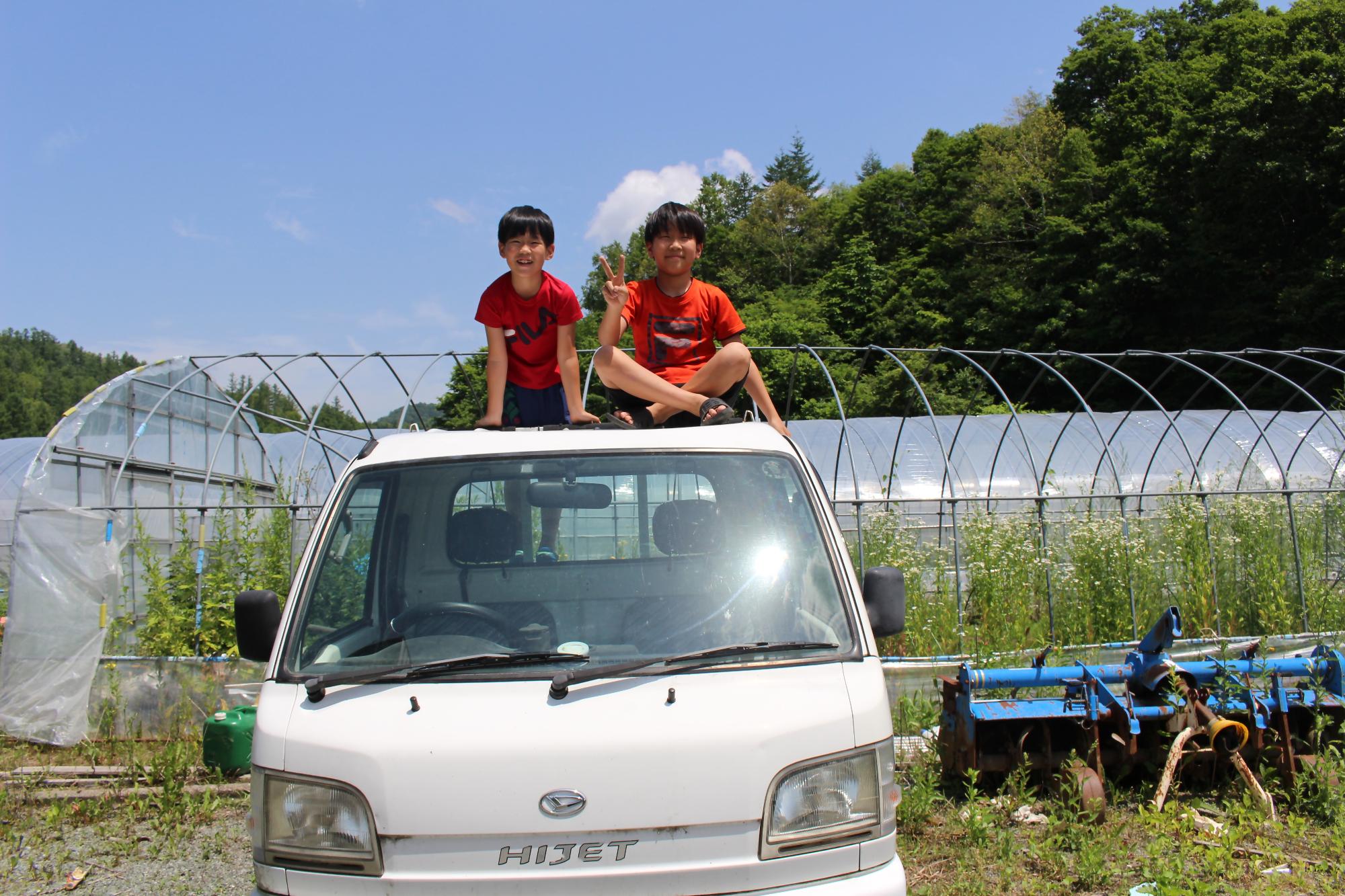 江崎さんご家族のお子さんたちが軽トラックの上で笑顔で映っている写真。