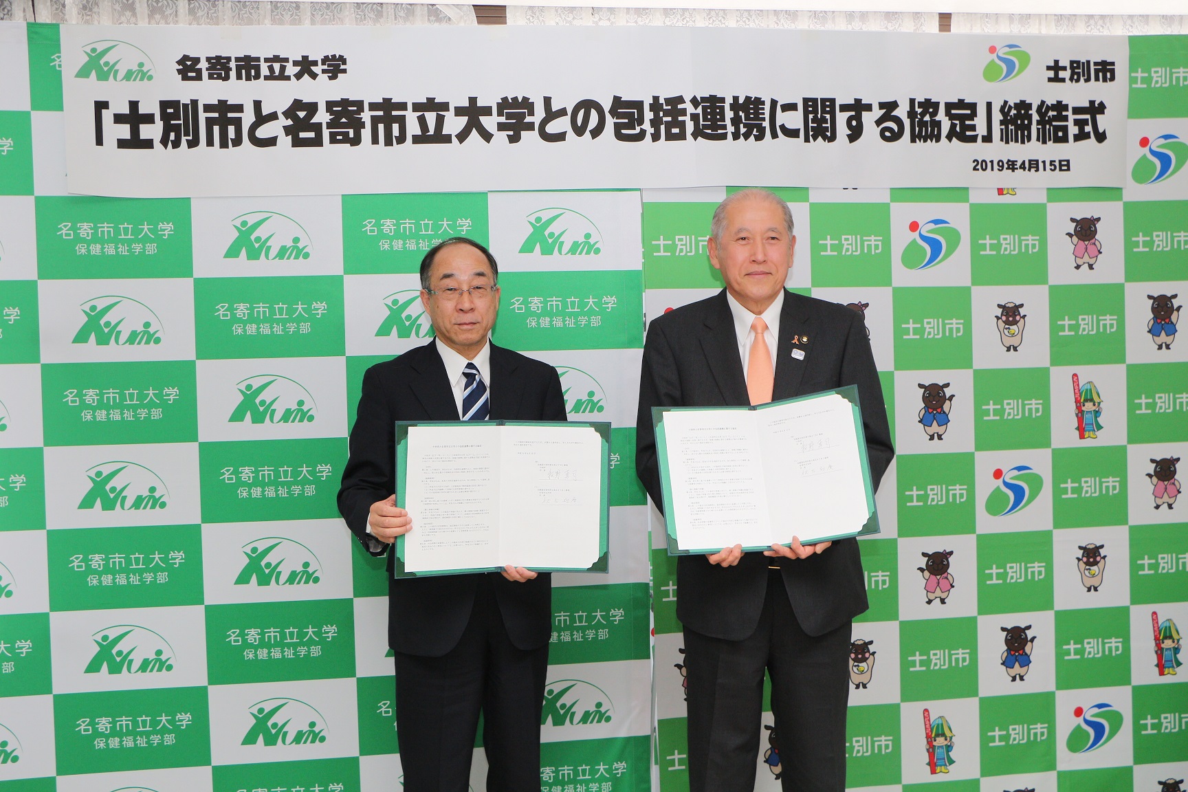 市長と名寄市立大学の代表の男性が包括連携協定書を持って撮影した記念写真