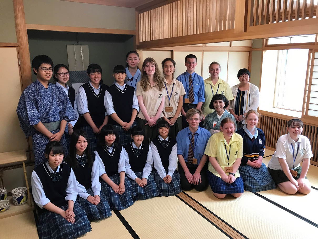和室に留学生と女子高校生達が正座をして記念撮影をしている写真