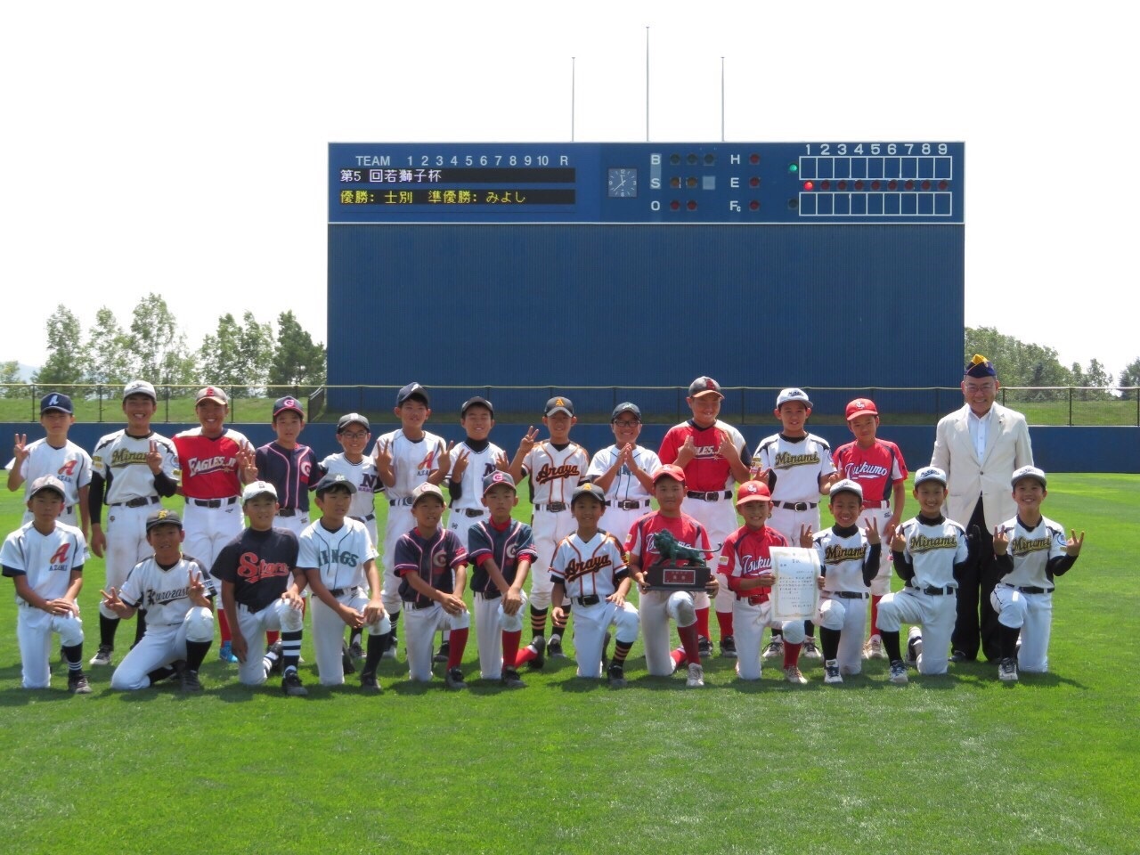 野球受入にてユニフォームを着た子供たちが野球場の芝生の上で写っている集合写真