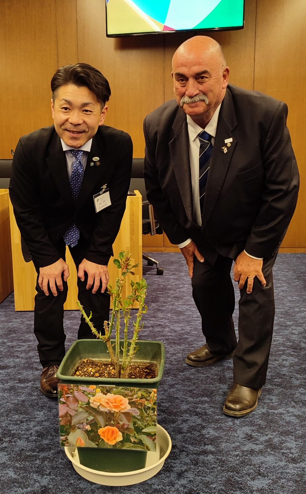 ゴールバーンマルワリー市長と士別市長がゴールバーンローズの鉢の後ろで記念撮影している写真