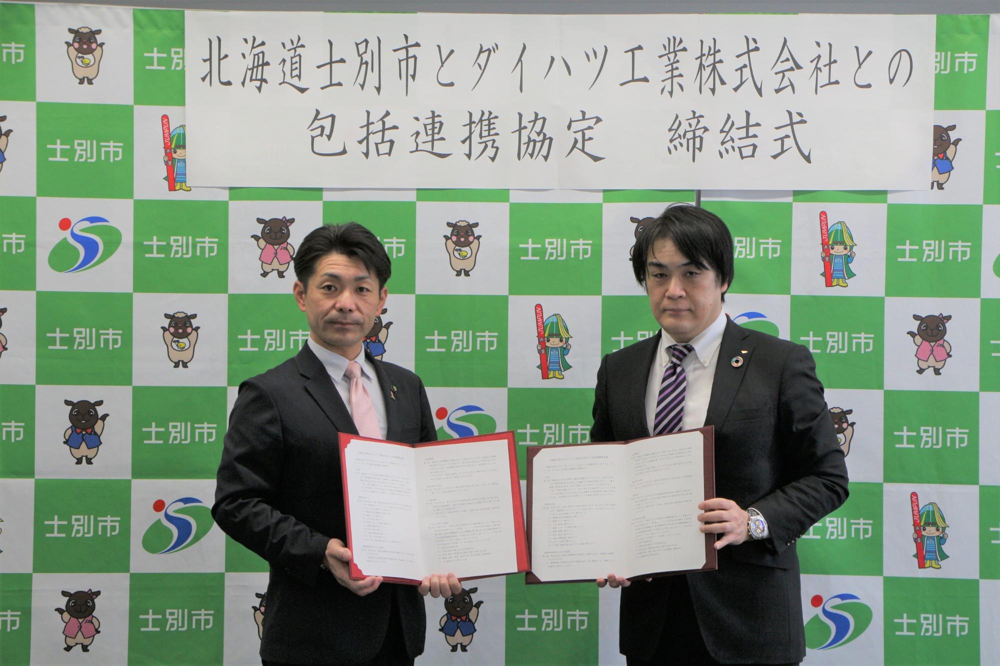 北海道士別市とダイハツ工業株式会社との包括連携協定締結式で市長と豊田統括部長が協定書を見せながら記念撮影をしている写真