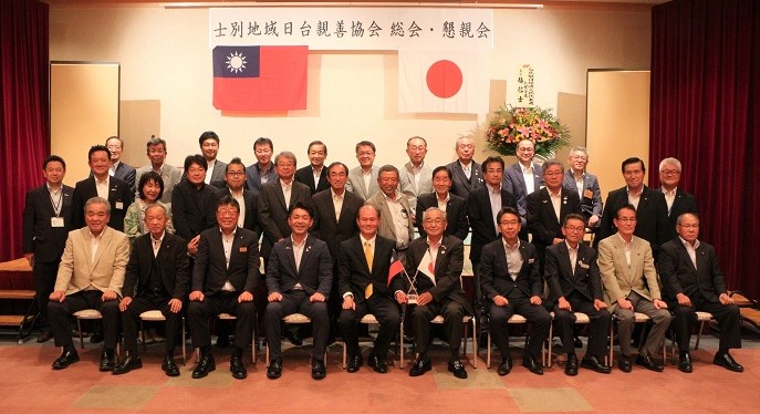 士別地域日台親善協会 総会・懇親会と書かれた幕の下で懇親会後の記念撮影を行っている写真