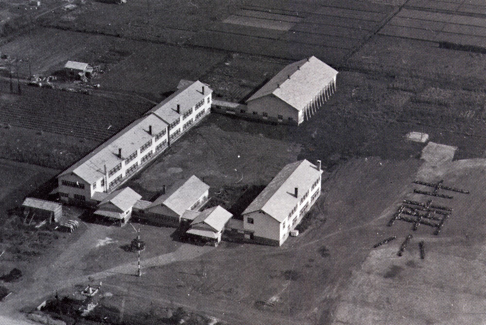 渡り廊下で繋がっている6棟の校舎の右側の校庭に人文字で「士南小」と書かれた昭和30年代の士別南小学校を上空から撮影した白黒写真