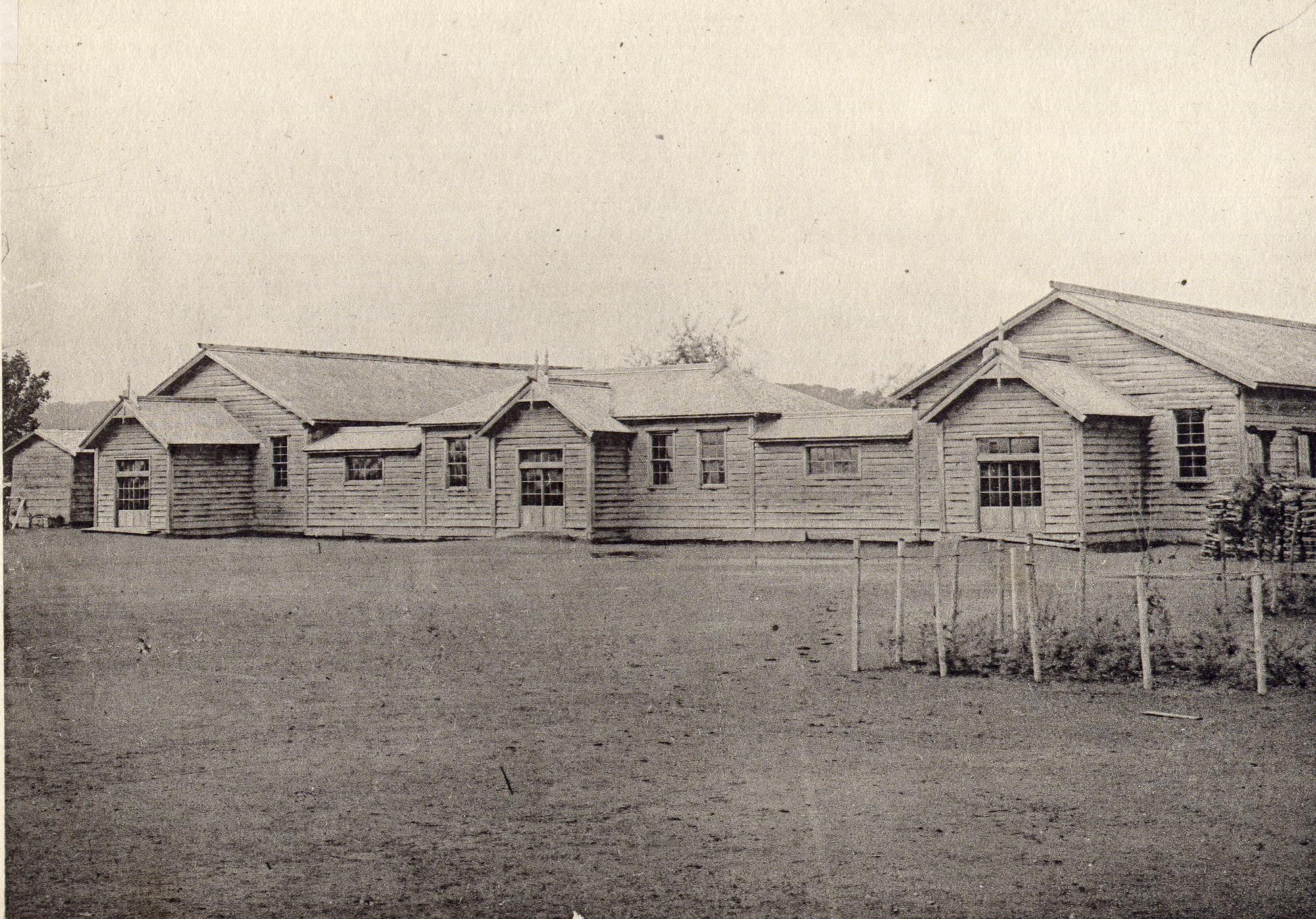 3棟の校舎が屋根付きの渡り廊下で繋がっている大正時代の上士別小学校の校舎の白黒写真