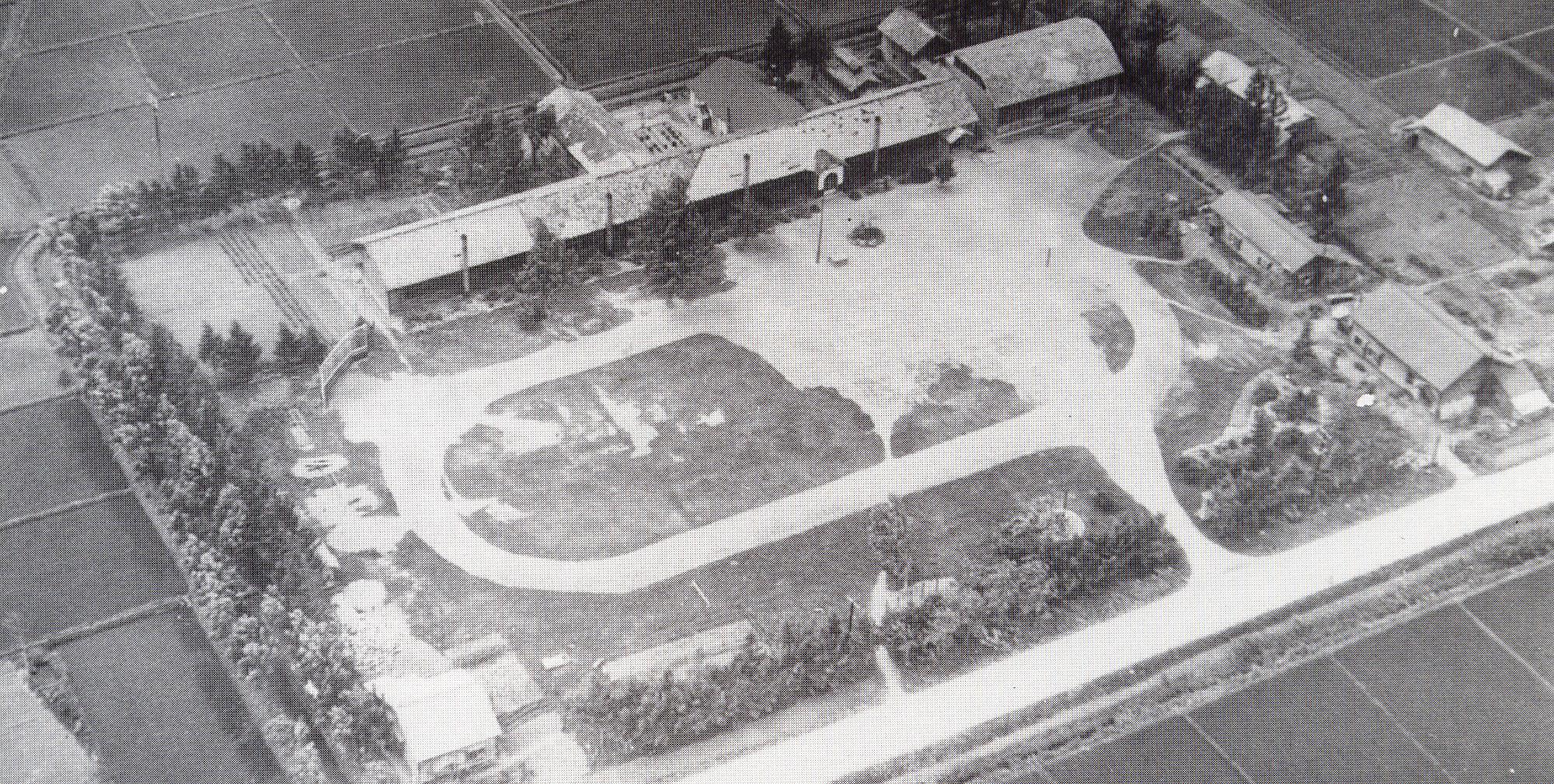 敷地上に校舎が建ち、手前に運動場が整備された昭和30年頃の下士別小学校を上空から撮影した白黒写真