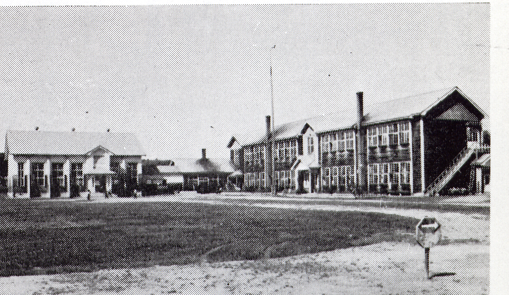 L字型の造りをした2階建ての旧川南小学校校舎を校庭から撮影した白黒写真