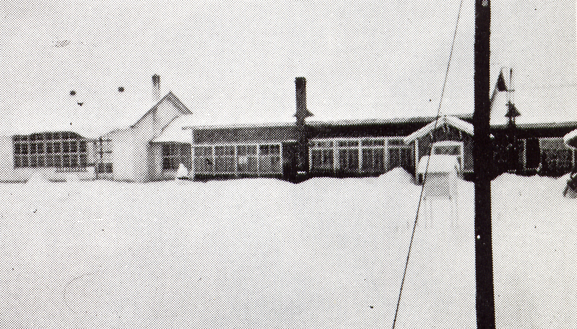 屋根や校庭に雪が降り積もった1階建ての旧南沢小学校校舎の白黒写真