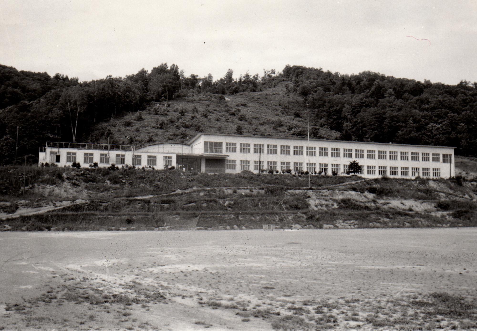 小高い山の麓に建てられた2階建ての昭和37年の糸魚小学校校舎を校庭から撮影した白黒写真
