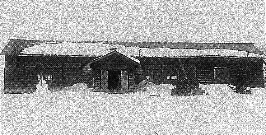 屋根や校庭に雪が降り積もり横長で中央に入り口が設けられている東陽小学校の白黒写真