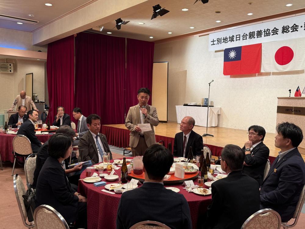 士別地域日台親善協会 総会・懇親会と書かれた幕の下で懇親会後の記念撮影を行っている写真