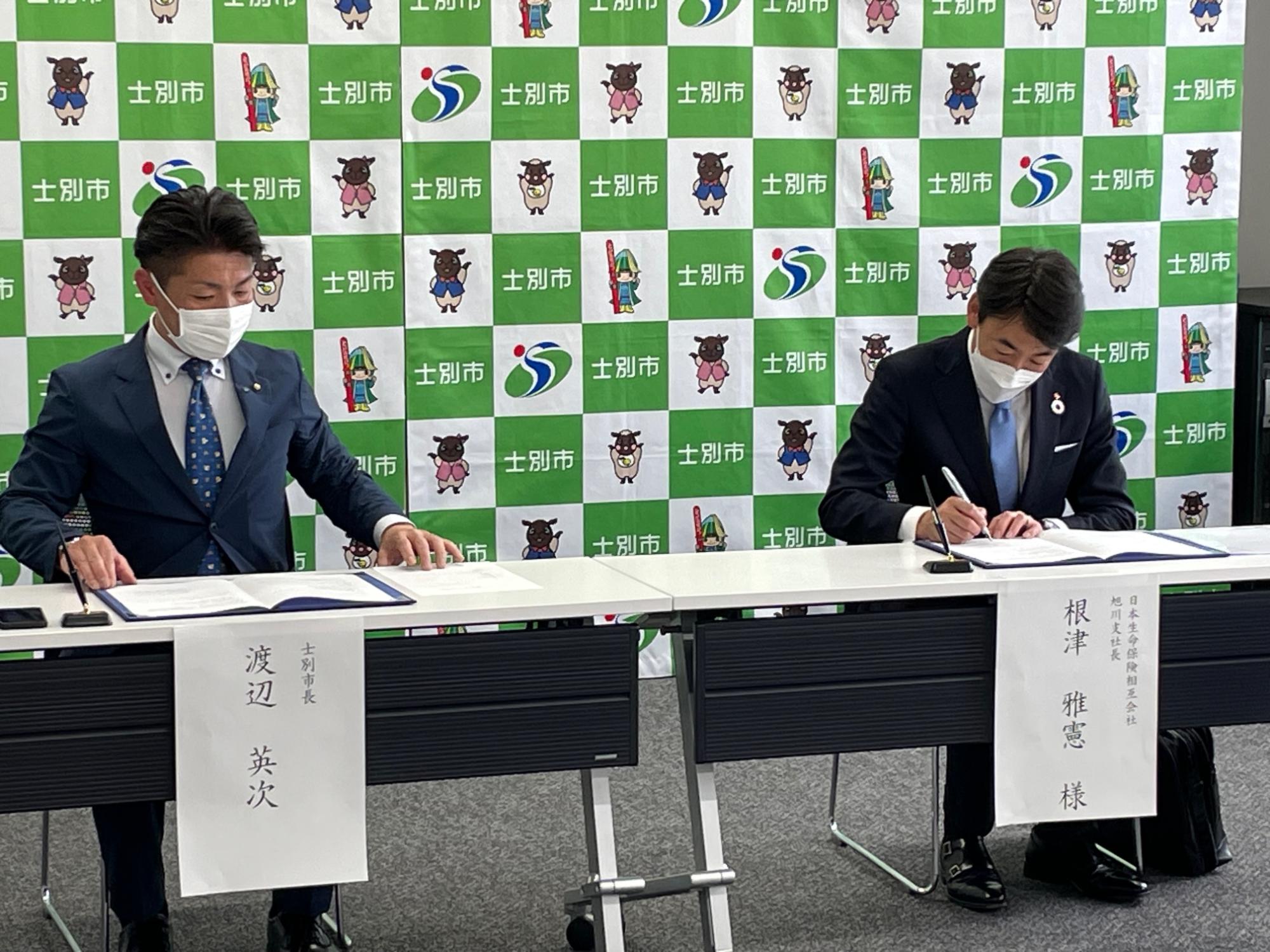 渡辺市長と根津支社長が協定書にサインをしている写真
