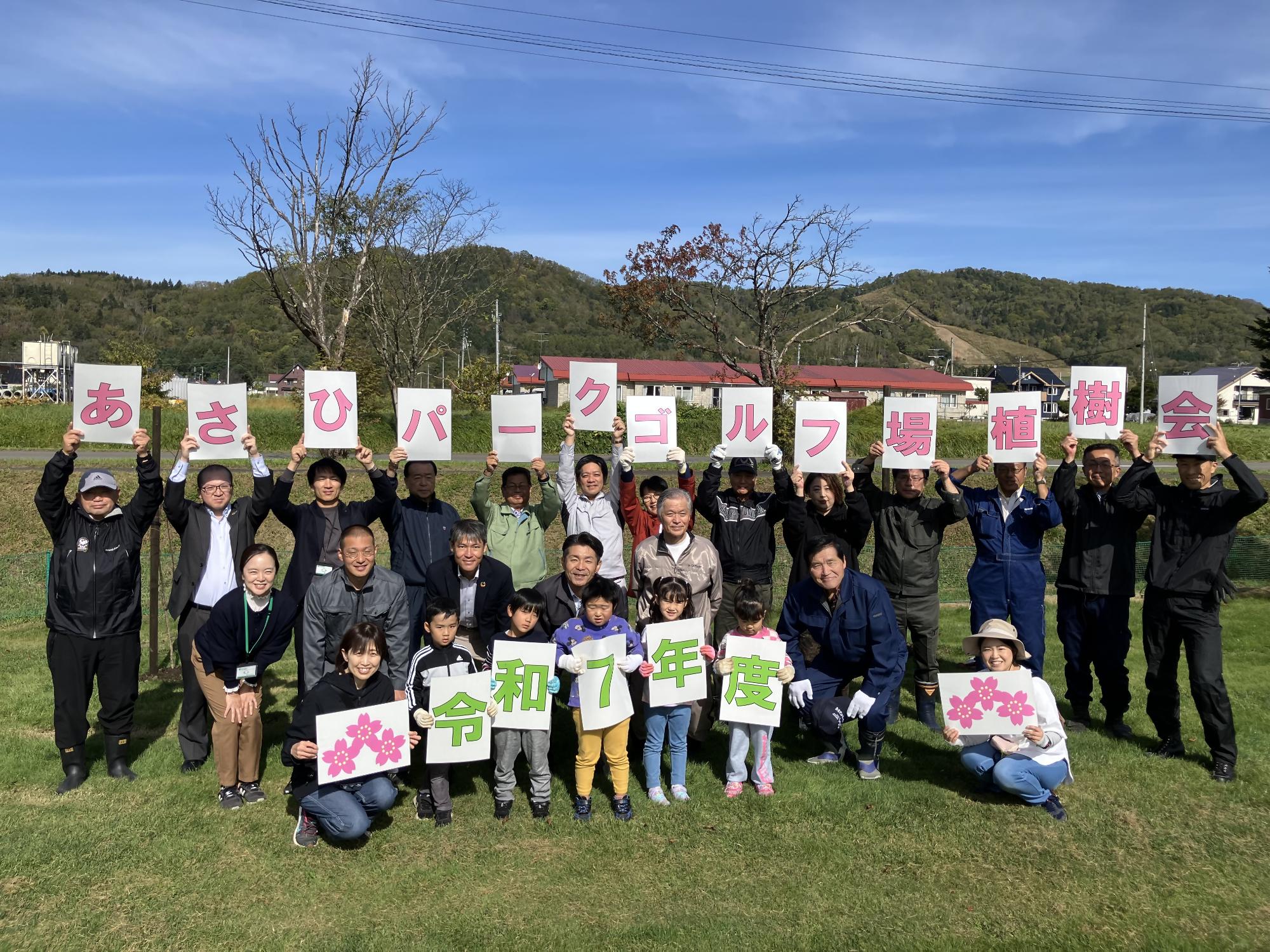 エゾヤマザクラの苗木を植樹した後の市長・市議会議員・北海道銀行職員・園児・保育士との集合写真