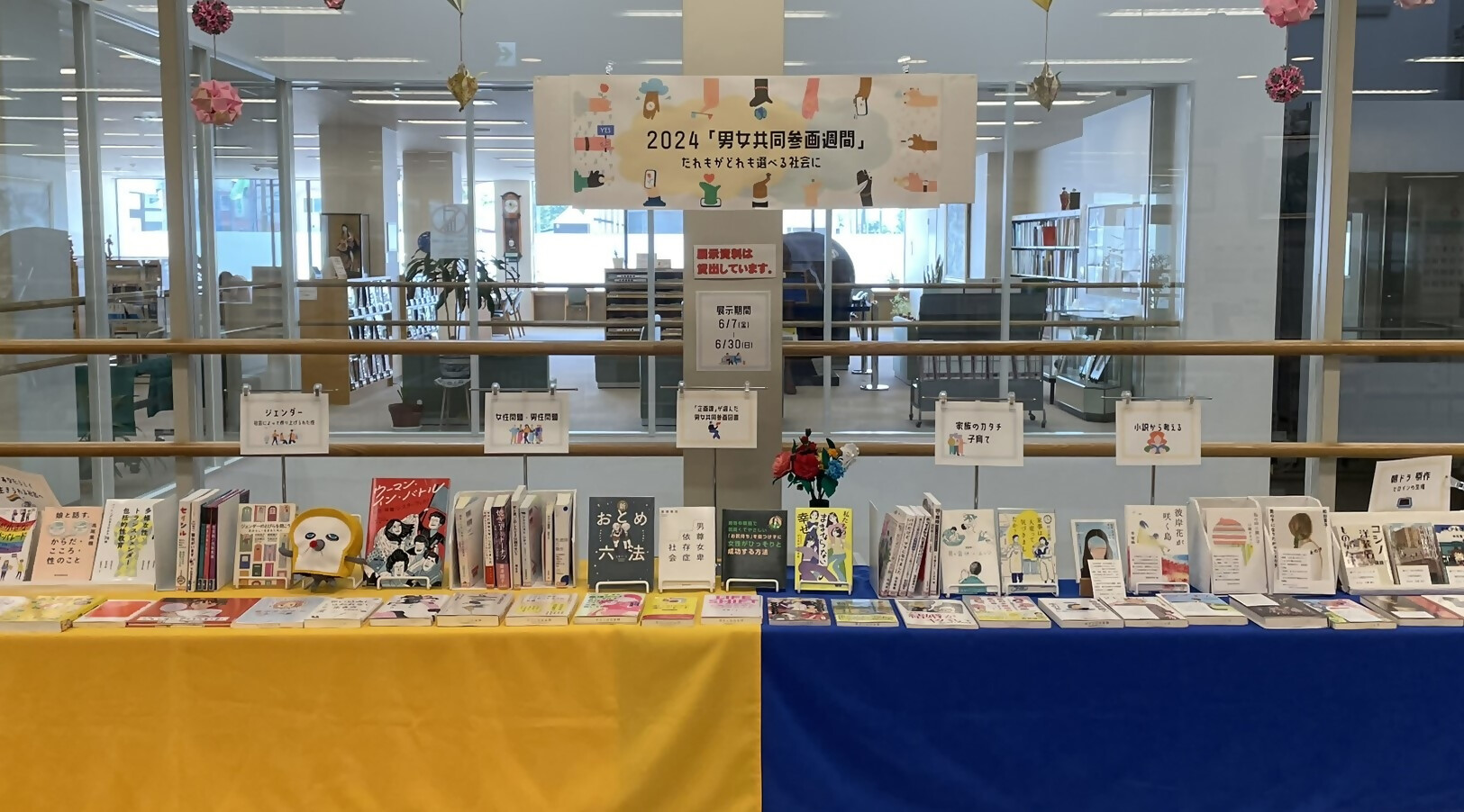 男女共同参画週間と書かれたパネルの下にたくさんの本が展示された図書館内の写真
