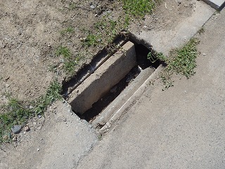 道路側溝の一部が破損して穴が開いている写真