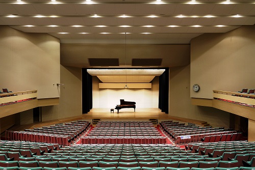 ステージ中央にグランドピアノが設置され、左右に2階席を設けている大ホールの写真